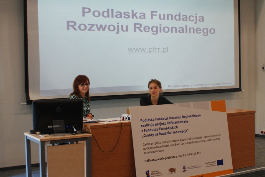 Dwie pracownice Fundacji prezentują możliwości otrzymania grantów, za nimi prezentacja multimedialna 