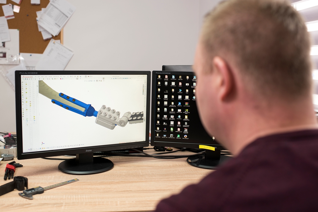 Pracownik firmy IWET siedzi przed ekranem komputera i projektuje implant