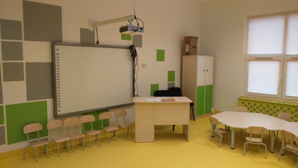 Wnętrze sali dydaktycznej, biurko, ławki, tablica multimedialna, rzutnik