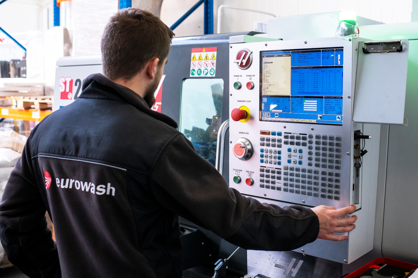 Employee stands in front of a machine and monitors the operation of a system 